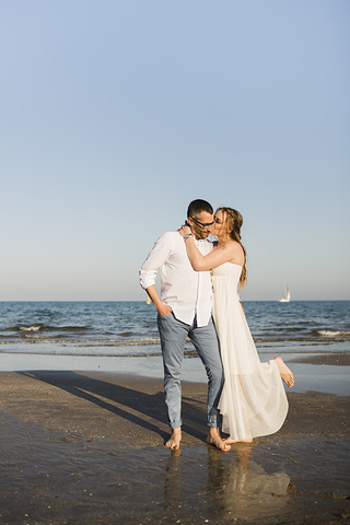 wife-kissing-her-husband-near-the-seashore-at-beach_23-2148103060