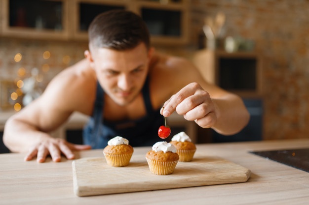 naked-man-in-apron-cooking-dessert-on-the-kitchen_266732-5808